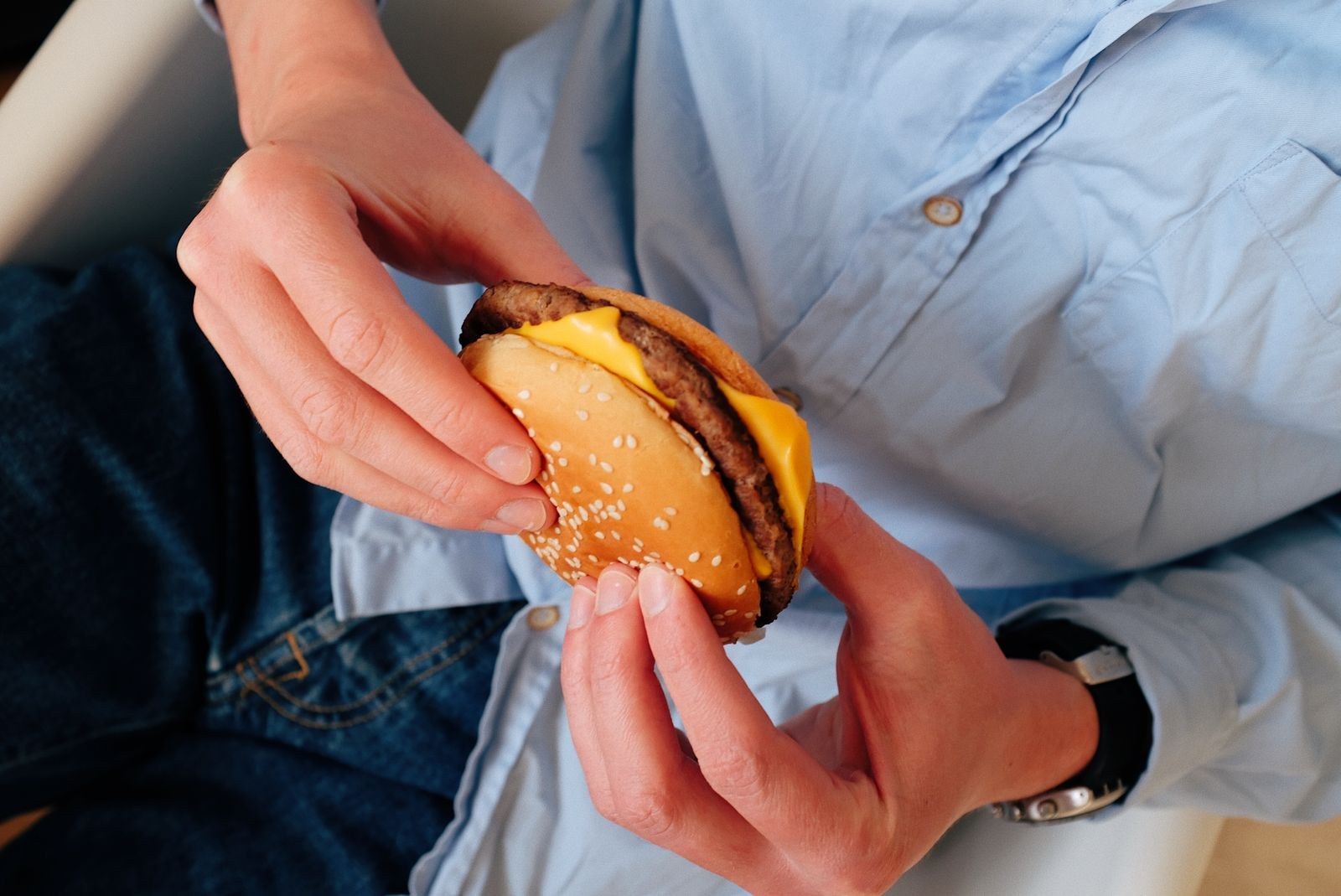 Mãos segurando um cheeseburguer